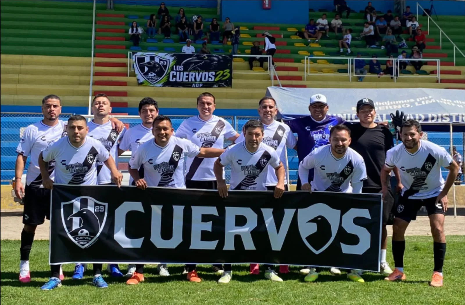 Cuervos 23 AQP con la camiseta oficial y bandera del club en el Estadio Municipal de Sachaca.